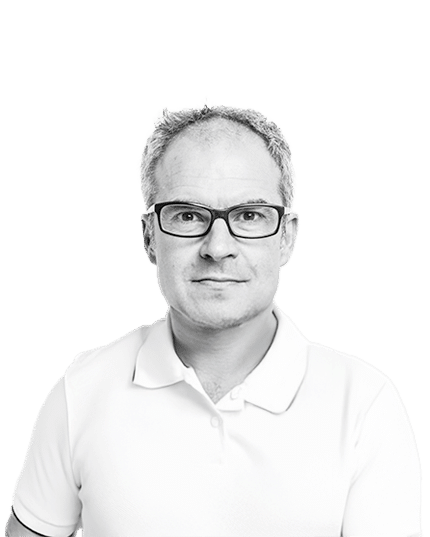Black and white headshot of a man wearing glasses and a white polo shirt, looking confidently at the camera against a plain light background.
