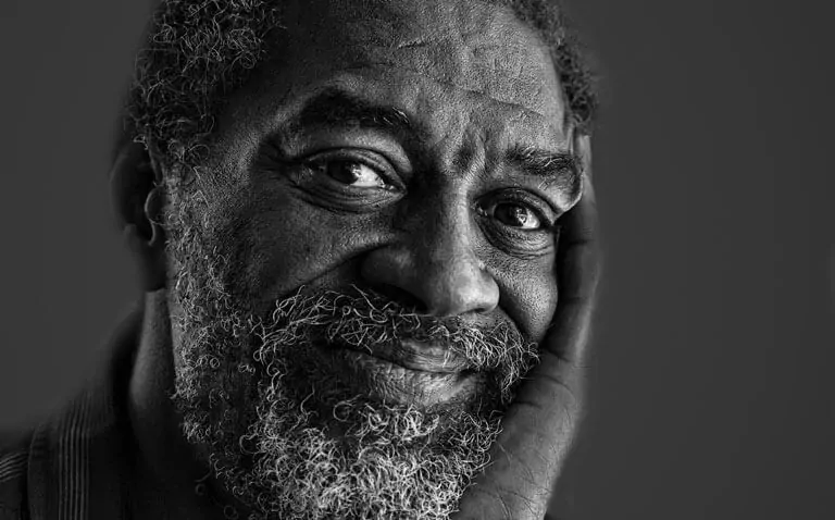 Portrait of an older man with a beard, resting his face on his hand, black and white photo