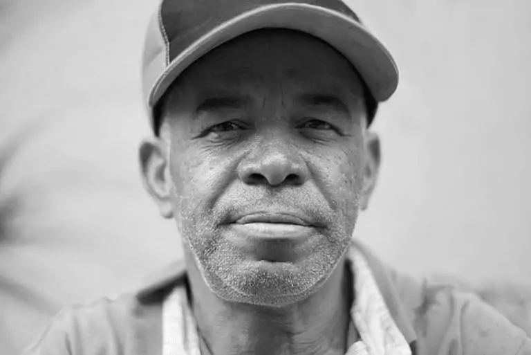 Black and white portrait of an older man wearing a cap, looking at the camera