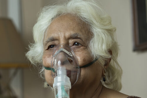 Senior woman with oxygen mask at home to illustrate Progressive Pulmonary Fibrosis (PPF)