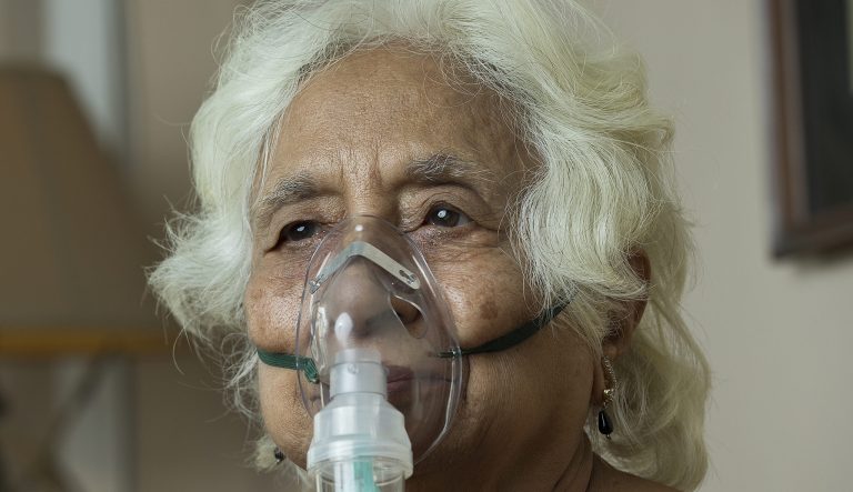 Senior woman with oxygen mask at home to illustrate Progressive Pulmonary Fibrosis (PPF)